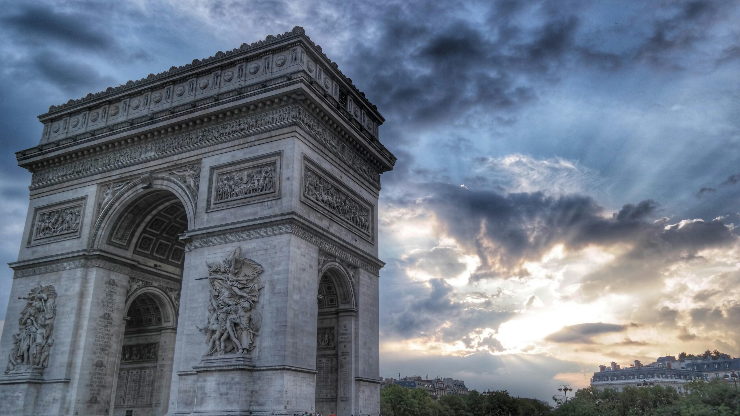 Stunning view of the iconic Arc de Triomphe under a dramatic sky in Paris.