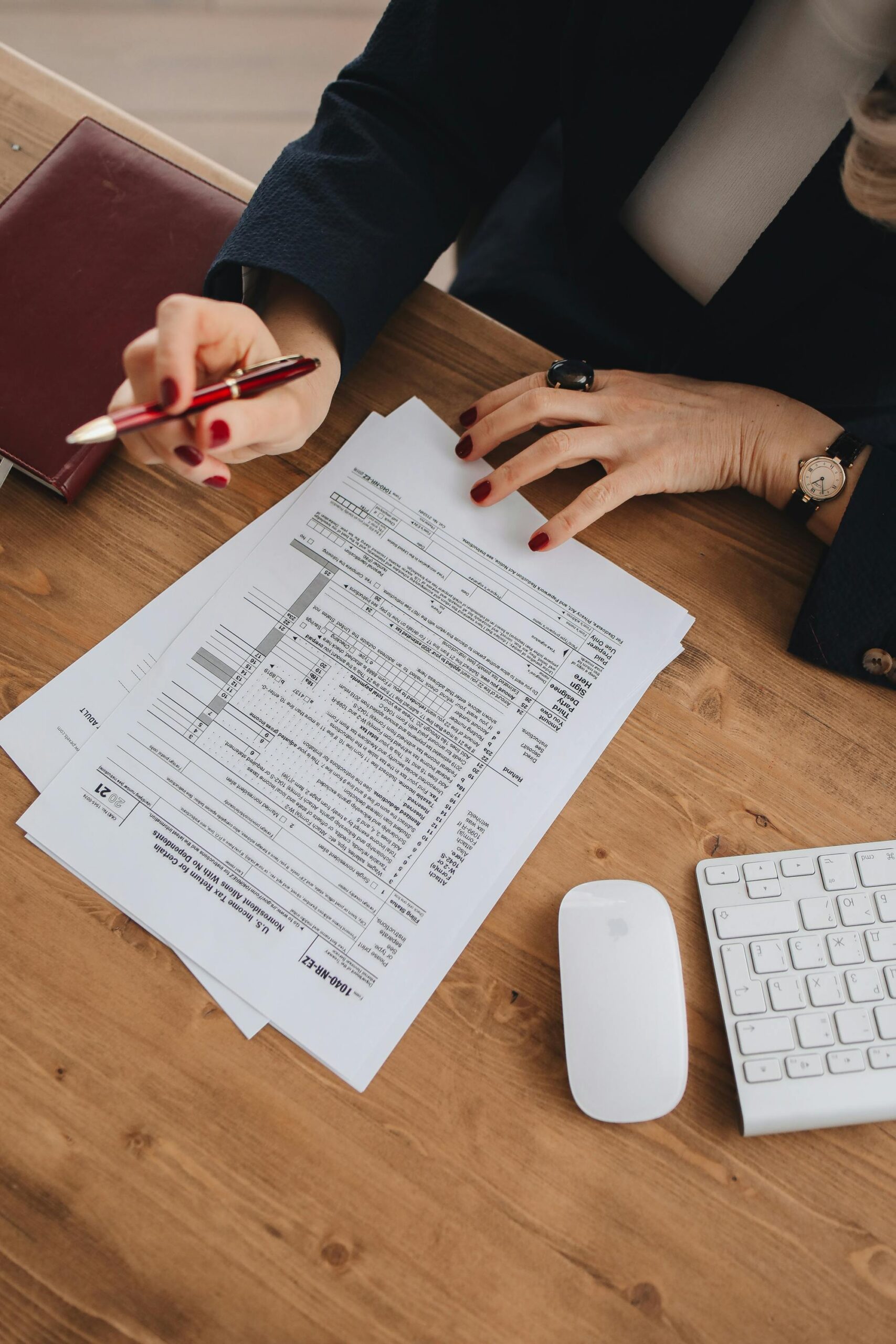 Top view of a business professional checking tax documents on a wooden desk.